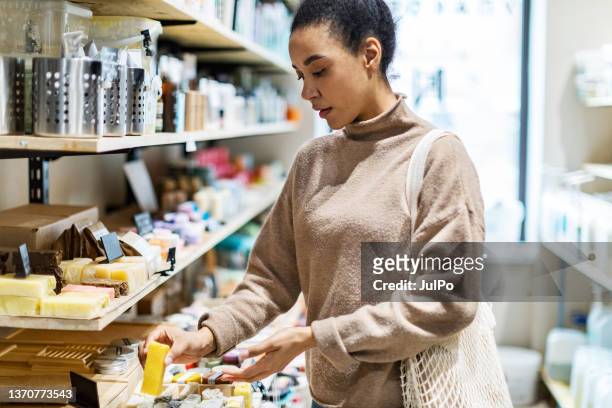 une jeune femme africaine fait ses courses dans un magasin zéro déchet - magasin cosmétique photos et images de collection