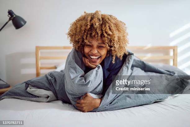 retrato de una hermosa mujer en la cama acurrucada bajo las sábanas - duvet fotografías e imágenes de stock