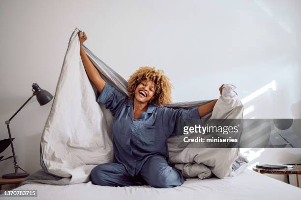 happy woman playing with her bed covers in the morning - duvet stock pictures, royalty-free photos & images