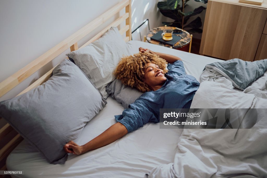 Hermosa mujer alegre que tiene un fin de semana perezoso en la cama