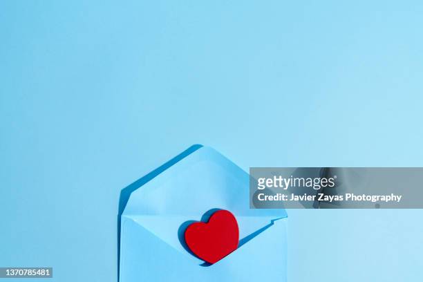 open blue envelope with a love message inside on a blue background - love letter stock-fotos und bilder