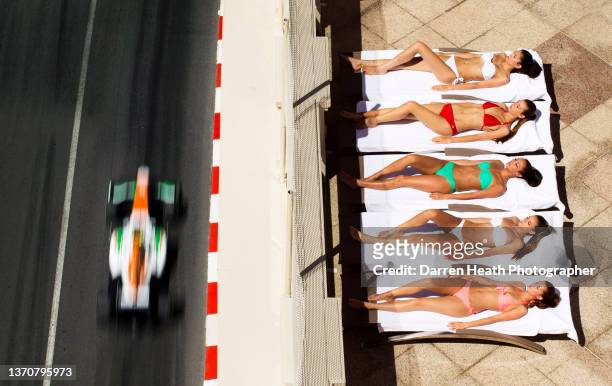 Photographed from above, German Force India Formula One team racing driver Adrian Sutil driving his VJM06 racing at speed past five multi coloured...