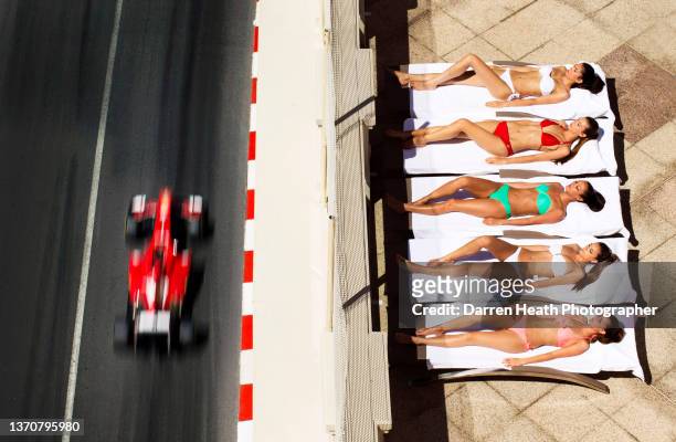 Photographed from above, Spanish Scuderia Ferrari Formula One team racing driver Fernando Alonso driving his F138 racing at speed past five bikini...