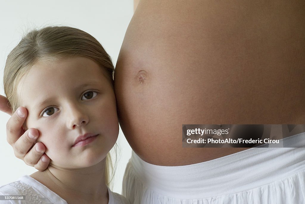 Girl listening to mother's pregnant belly