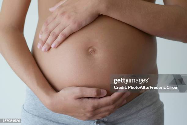 pregnant woman holding her belly, cropped - embarazada fotografías e imágenes de stock