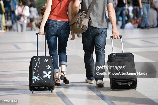 couple walking outdoors with rolling luggage - low section woman stock pictures, royalty-free photos & images