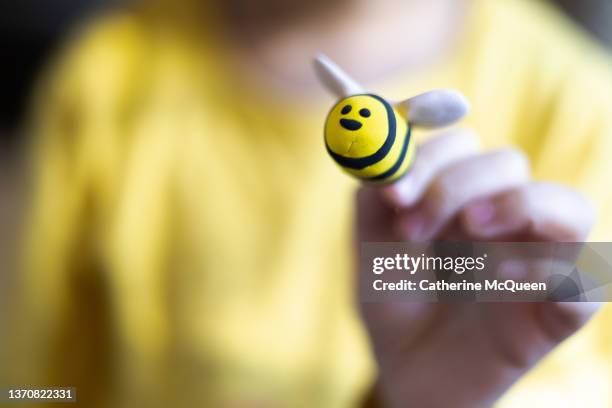 young mixed-race child wearing bright yellow shirt & holding cute yellow bumblebee made of clay - african american girl wearing a white shirt stock pictures, royalty-free photos & images