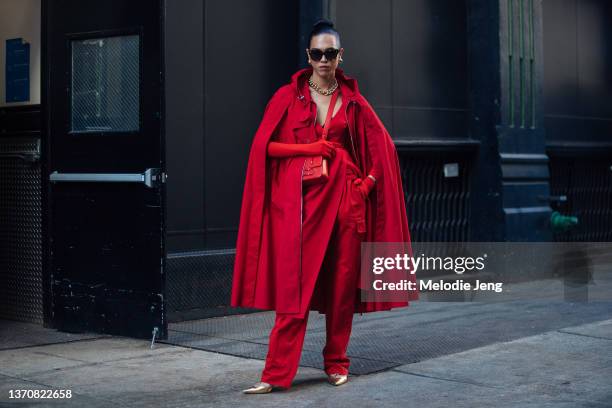 Model and stylist Dara Allen wears an all-red outfit including a red cape jacket, dress, pants, and Carolina Herrera bag, along with gold heels at...