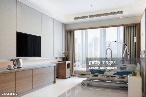 intérieur moderne de la chambre d’hôpital de luxe avec lit vide, télévision lcd et vue sur la ville depuis la fenêtre - lit dhôpital photos et images de collection