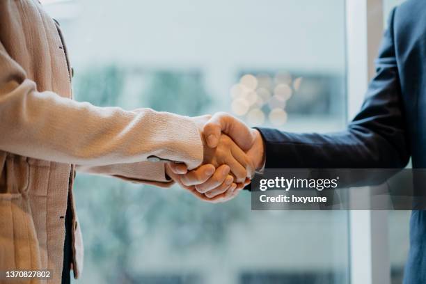 asian businesswoman and businessman shaking hands in office - gratitude stock pictures, royalty-free photos & images