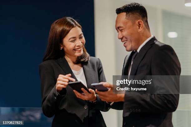 malay businessman and businesswoman using smartphone in office - malayan ethnicity stock pictures, royalty-free photos & images