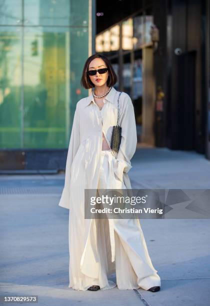 Chriselle Lim seen wearing button up dress in creme white, pants, cropped top, necklace, sunglasses, black bag outside Peter Do during New York...