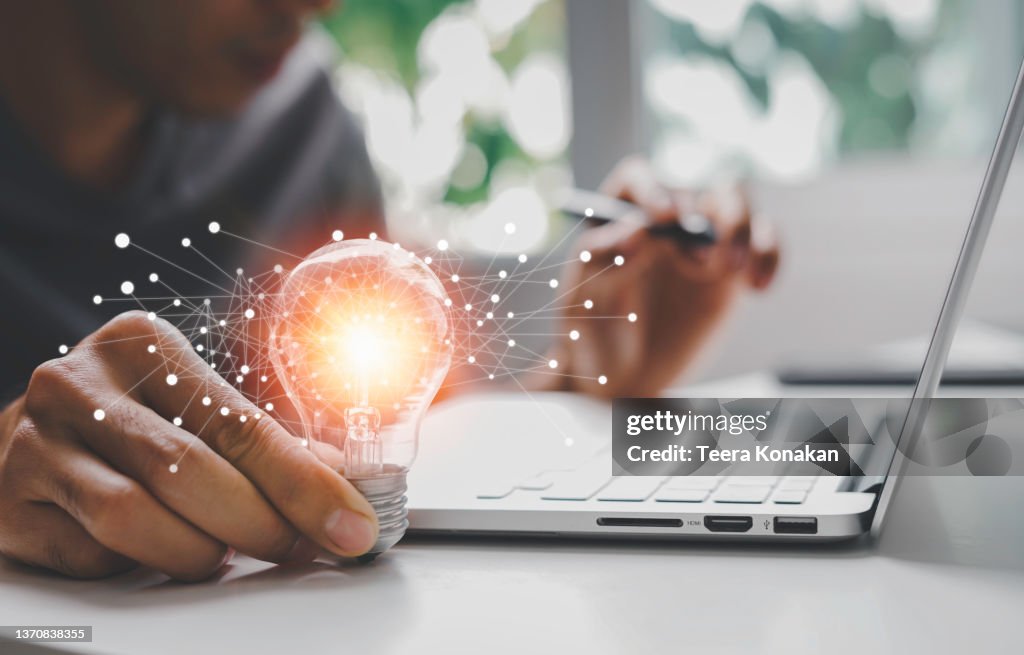 Male hand holding illuminated light bulb of new ideas with innovative technology and creativity
