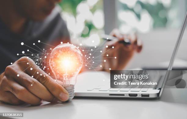 male hand holding illuminated light bulb of new ideas with innovative technology and creativity - idée foto e immagini stock