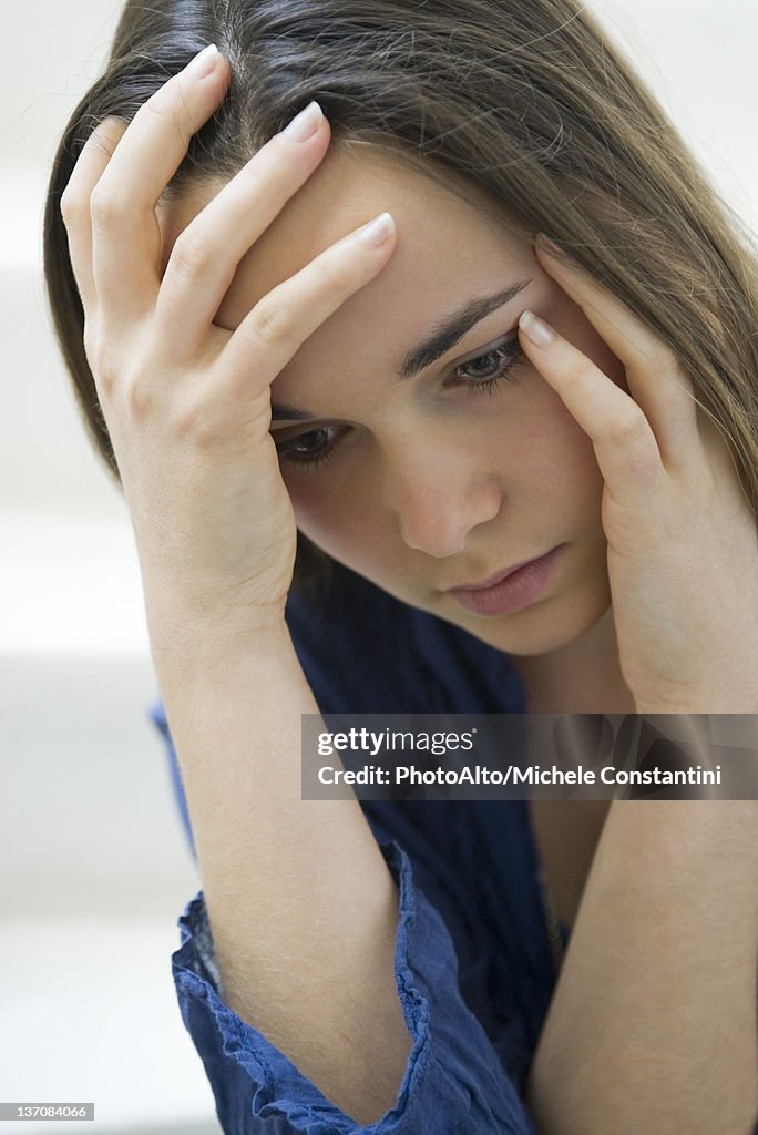 Young woman holding head and looking down