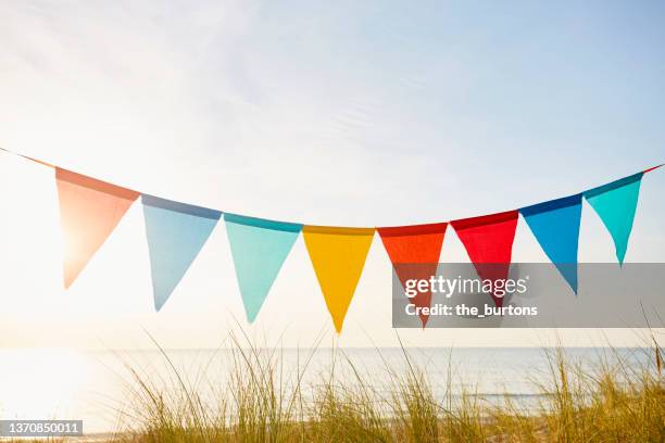 colorful bunting flags/ pennant chain for party decoration by the sea during sunset - vlag planten stockfoto's en -beelden