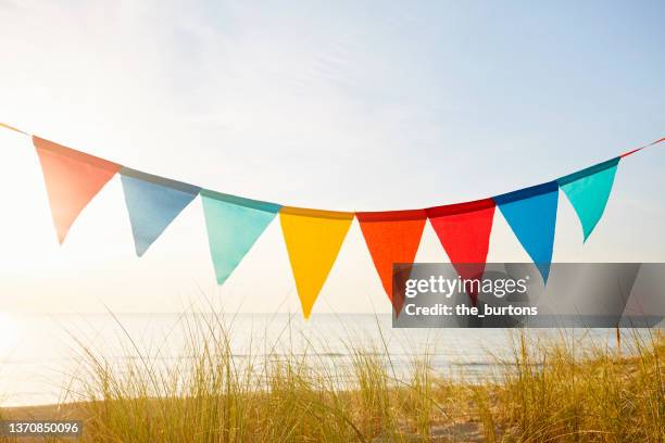 colorful bunting flags/ pennant chain for party decoration by the sea during sunset - bandierine foto e immagini stock