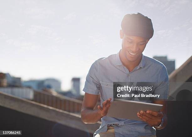 man using digital tablet on sunny urban rooftop - convenience stock pictures, royalty-free photos & images