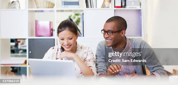 businessman and businesswoman using laptop in office - samuser stock pictures, royalty-free photos & images