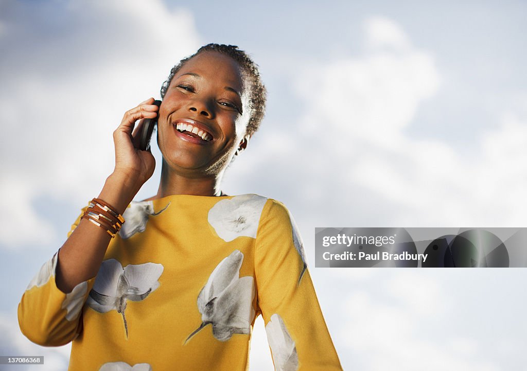 Retrato de mulher sorridente no telemóvel sob azul