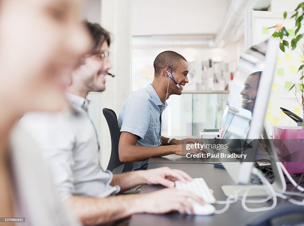 Business people with headsets working at computers in office