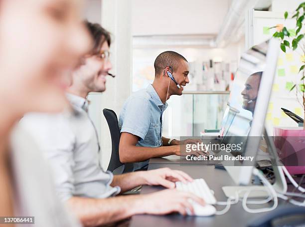 pessoas de negócios com auscultadores trabalhando em computadores no escritório - subcontratação imagens e fotografias de stock