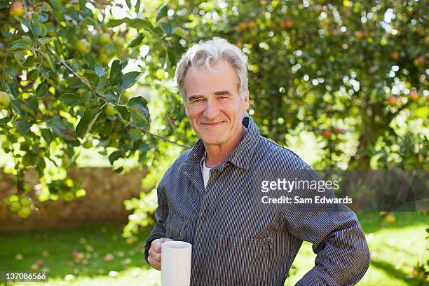 portrait de confiance homme senior boire du café dans un verger - 60 64 ans photos et images de collection