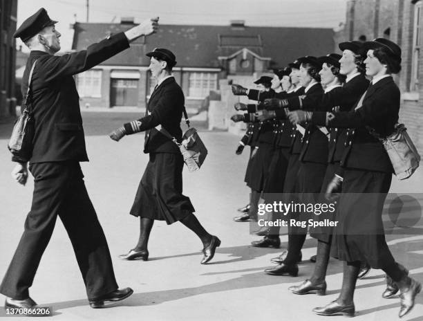 Royal Navy drill instructor demonstrates the correct method of march to a parade of Women's Royal Naval Service personnel led by Joan Carpenter ,...