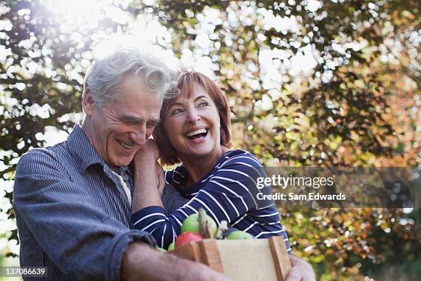 glücklich altes paar mit bushel von äpfeln umarmen - baby boomer couple stock-fotos und bilder