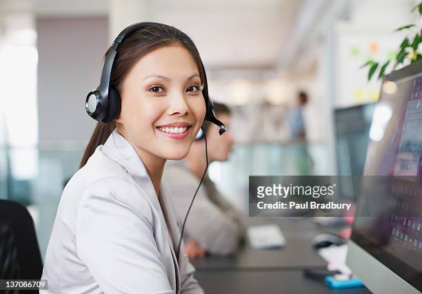 retrato de um sorridente mulher de negócios com auscultadores com microfone para computador em de - asian females on a phone imagens e fotografias de stock