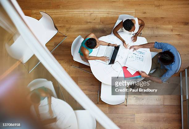 uomini d'affari che lavora su un tavolo con un computer portatile e documentazione - overhead view foto e immagini stock