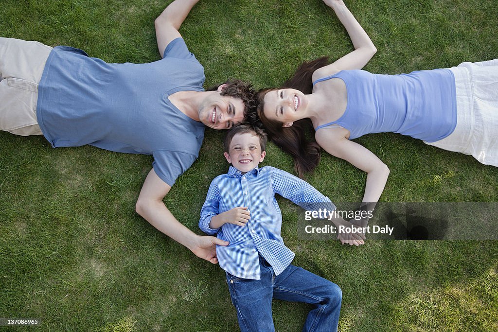 Portrait de souriant parents et fils sur herbe et tenant la main