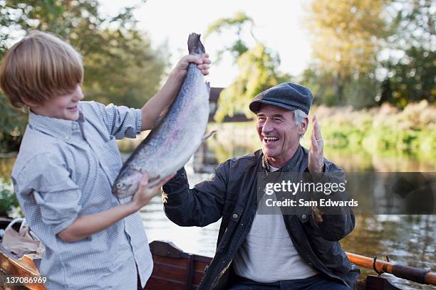 neto a captura de peixes com avô a celebrar em segundo plano - fish love imagens e fotografias de stock