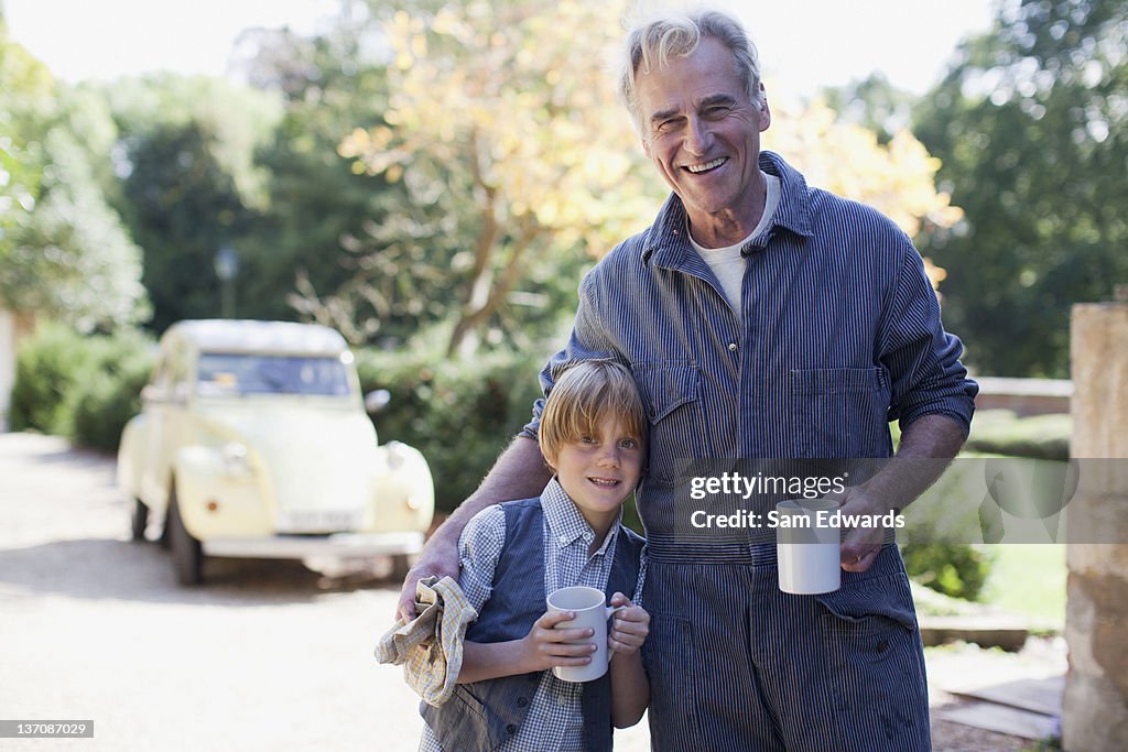 Retrato de sorrir avô e Neto agarrar com café