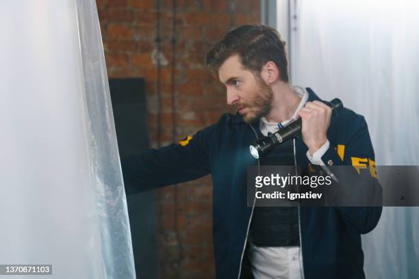 fbi agent at the crime scene, searching for criminals with flash light in hand - fbi warning stock pictures, royalty-free photos & images