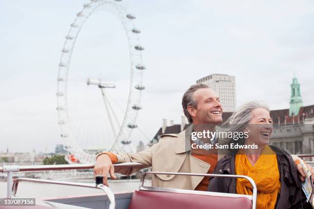 happy couple riding double decker bus in london - couple london stockfoto's en -beelden