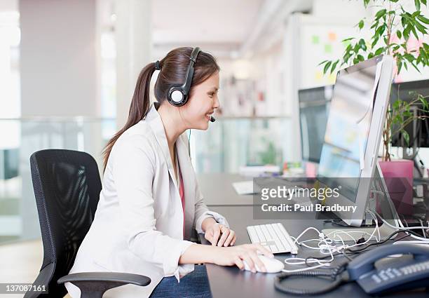 businesswoman with headset using computer in office - answering stock pictures, royalty-free photos & images