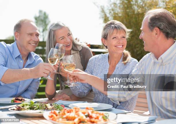 senior couples toasting wine glasses at patio table - four day old stock pictures, royalty-free photos & images