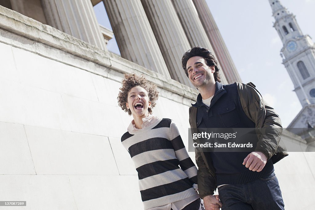 Happy couple walking along urban buildings