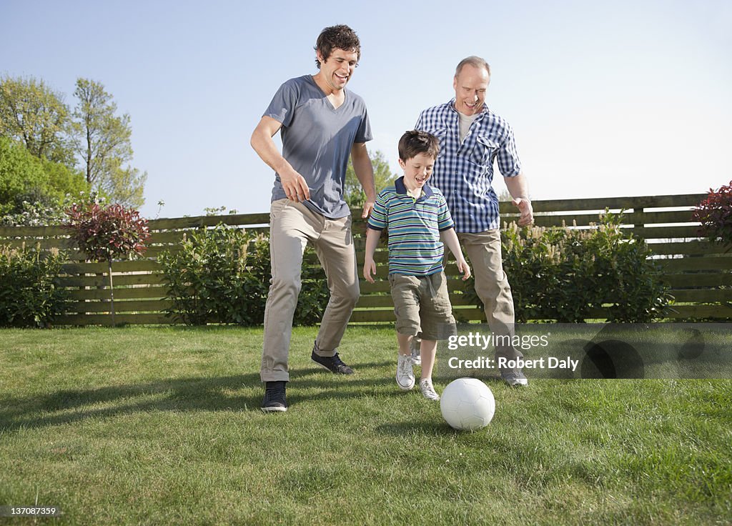 Multi-generation family playing soccer in backyard