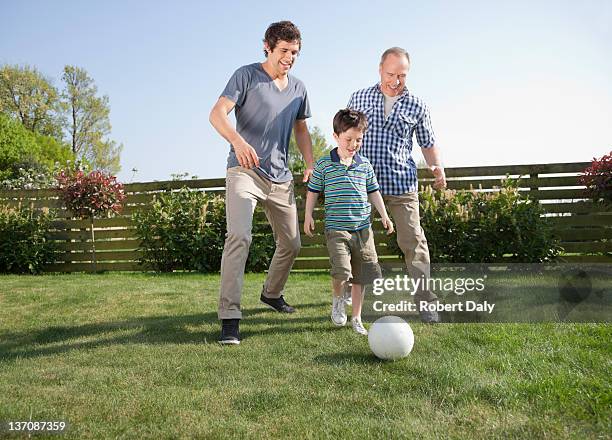 multi-generation family playing soccer in backyard - grandpa son stock pictures, royalty-free photos & images