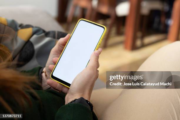 close-up, woman holding a smart phone in her hands and checking and looking at the cell phone screen. white screen. - banco de españa fotografías e imágenes de stock