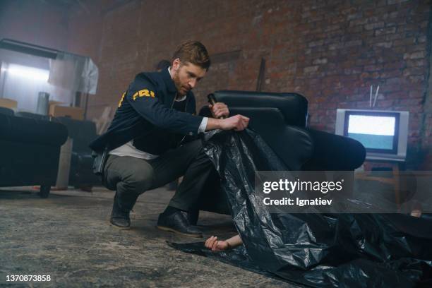 crime scene and a handsome fbi agent taking out a black plastic bag from the corpse - criminology stock pictures, royalty-free photos & images