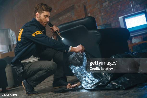 crime scene in abandoned storage room where the den of criminals was located and an fbi agent taking out a black plastic bag from the corpse - exclusive offer bildbanksfoton och bilder