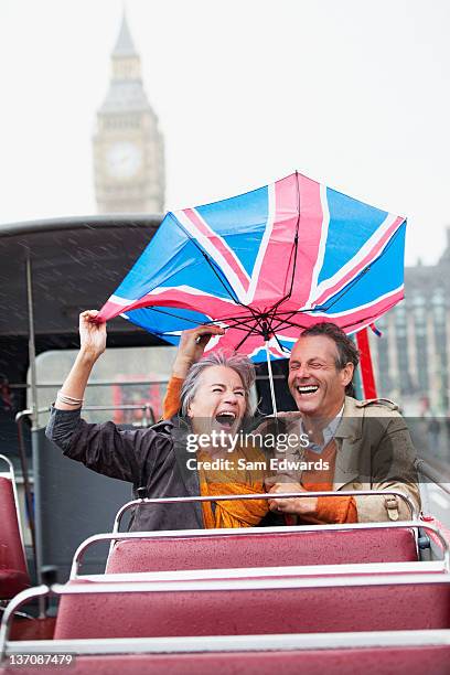 rain falling on couple with british flag umbrella on double decker bus - rain couple stockfoto's en -beelden