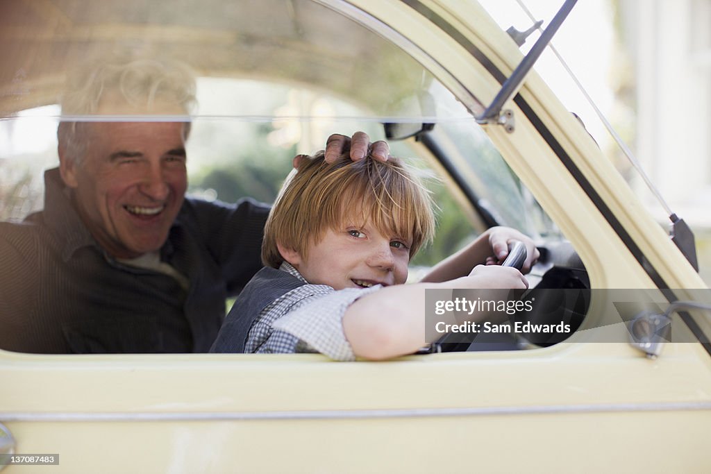 Portrait of grandfather and grandson behind steering wheel in car