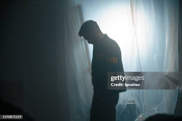 silhouette of an fbi agent at the crime scene in abandoned warehouse - fbi raid stock pictures, royalty-free photos & images