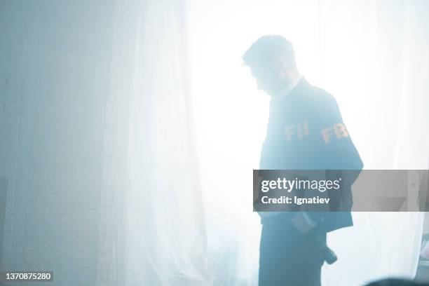 fbi agent in a a daylight, coming trough the big window, covered with a white curtain - fbi warning stock pictures, royalty-free photos & images