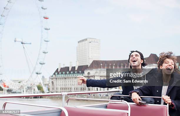exuberant couple riding double decker bus in london - autobus a due piani foto e immagini stock