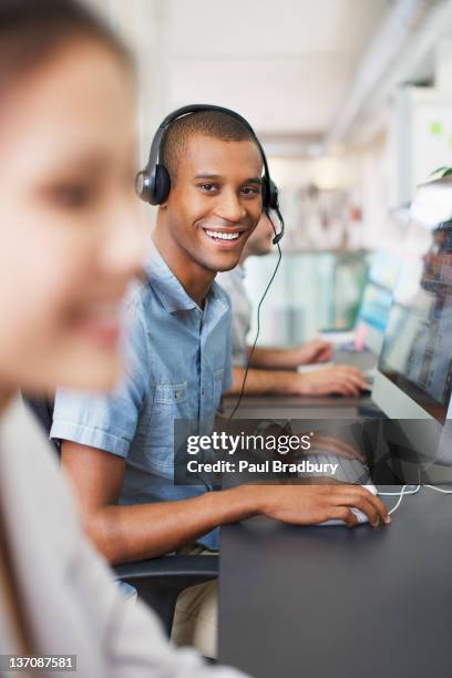porträt von lächelnd geschäftsmann mit headset im computer in office - freisprechanlage stock-fotos und bilder